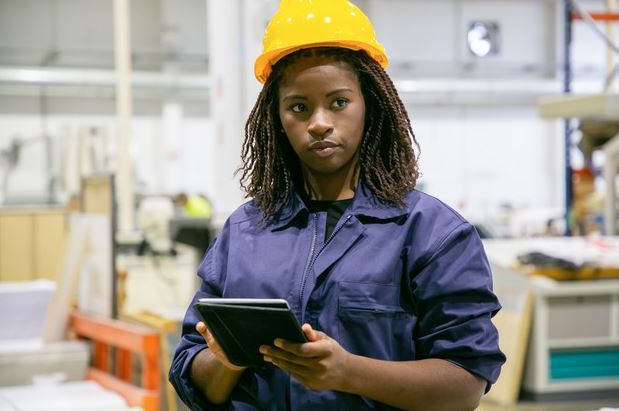Black women in the emerging black-owned supplier chain wearing a hard hat with note pad in her hands.