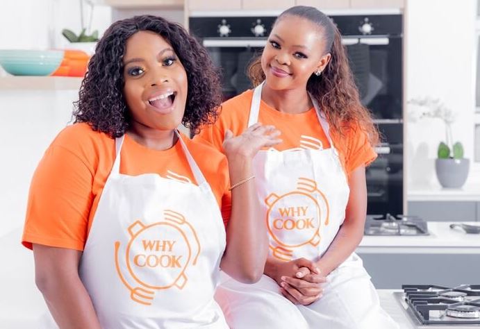 Two black entrepreneurs wearing aprons for cooking and sitting together.