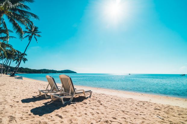 Two empty deck chairs on a sandy beach
