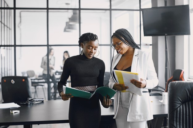 Black business women talking in the hallway while working during a course.