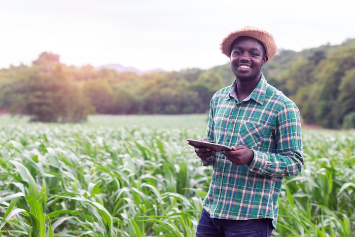 A smiling farmer holding a gadget