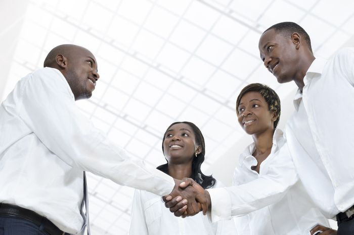 Black small business owner shacking hands with investors giving him a grant.