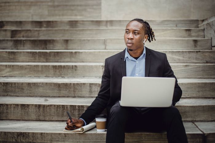 A black man sitting on stairs while working