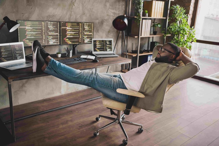 A man stretching his legs to his work desk
